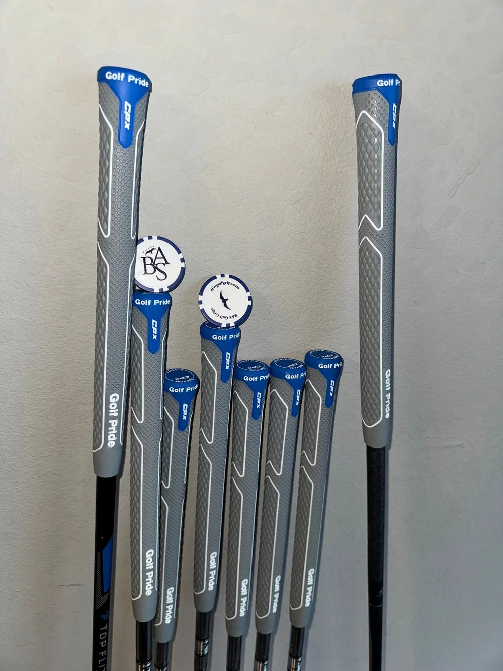 Completed gray and blue grip installation on a full set of clubs