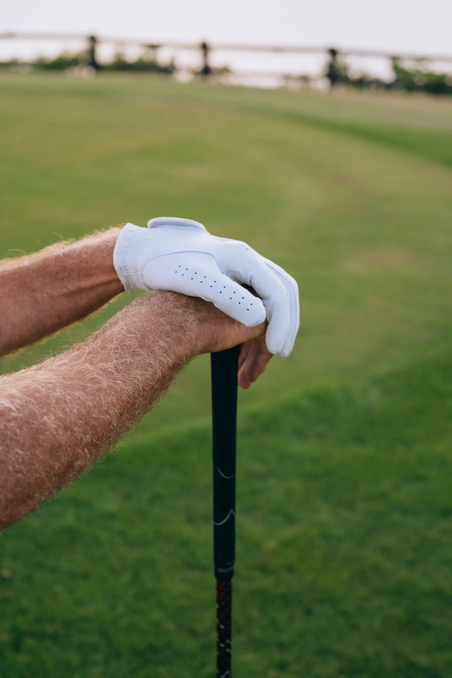 Golfer resting gloved hands on a club between shots