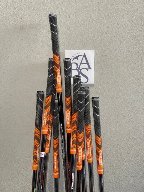 Collection of golf club shafts with orange and black wrapping with ABAS logo sticker