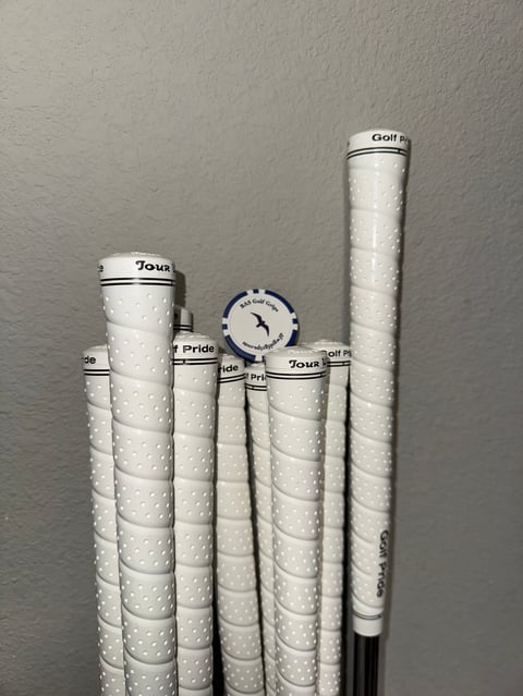 Collection of white golf club grips arranged vertically showing various brands and textures