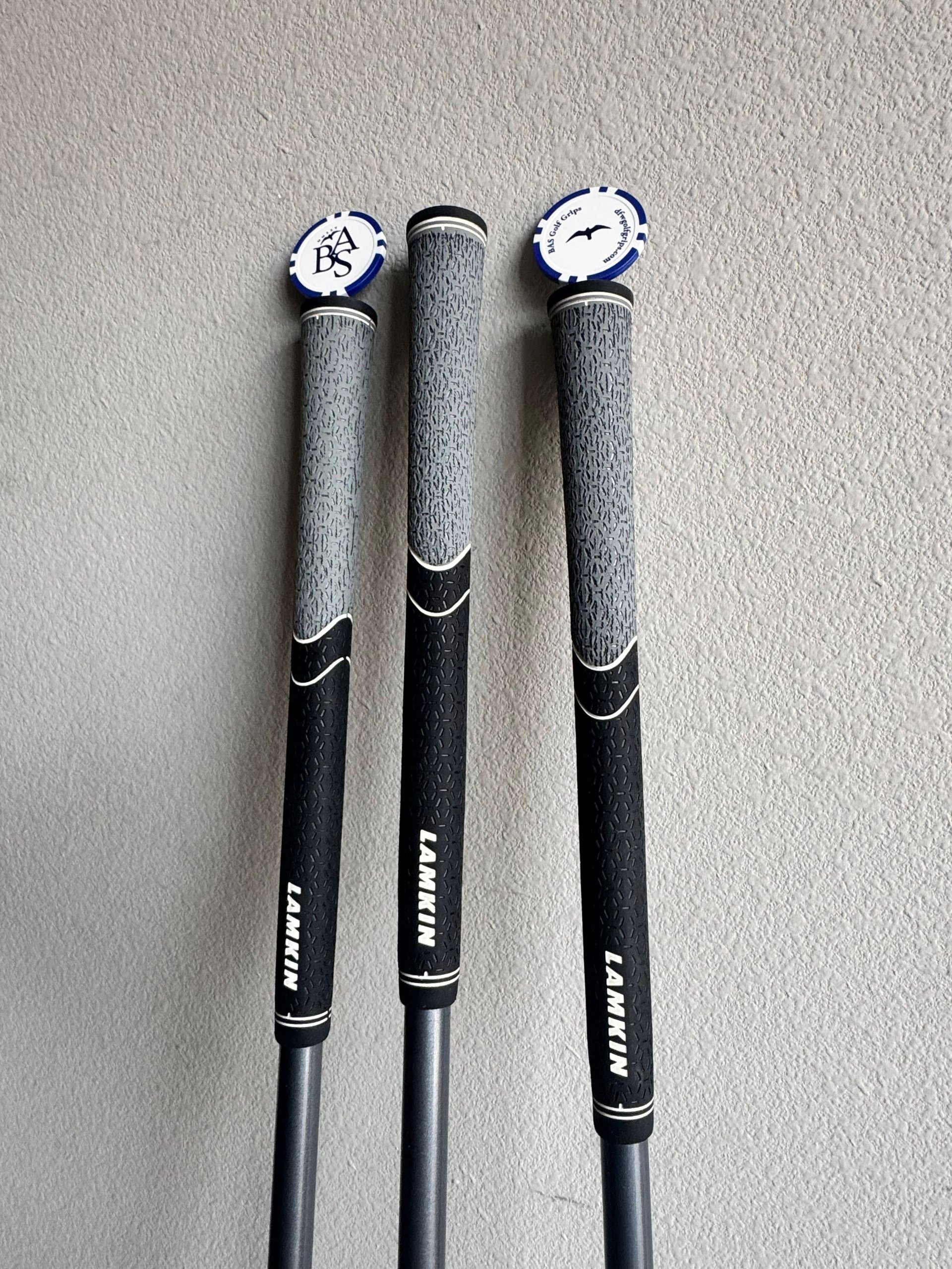 Three golf clubs with blue and white headcovers on a beige background